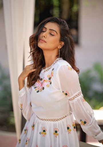 Woman wearing a white, floral embroidered dress with a flared hemline